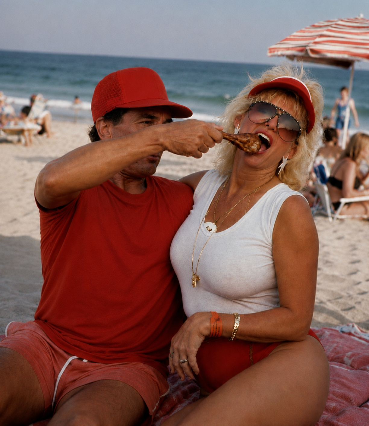 Couple sharing a chicken leg under a beach umbrella
