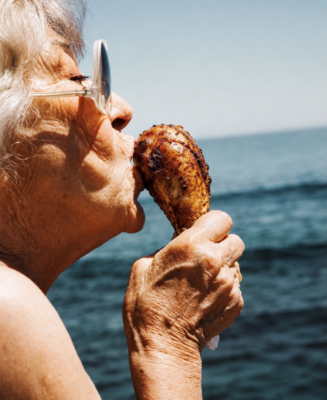 Grandma enjoying a chicken leg by the ocean
